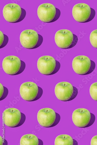 Pattern made of green apples on purple background. Minimal fruit concept. Apples pattern on ultra violet background. Organic and healthy food.