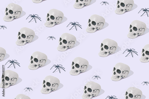 Fototapeta Naklejka Na Ścianę i Meble -  White skull and spiders on grey pastel background. Halloween minimal concept. Halloween mood. New Year’s greeting card. Pattern with skulls and spiders. Flat lay.