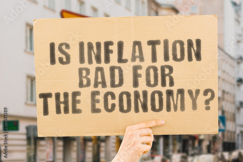 The question " Is inflation bad for the economy? " on a banner in men's hand with blurred background. Government. Politics. Economic crisis. Dangerous. Unemployment. Loss. Protect. Progress
