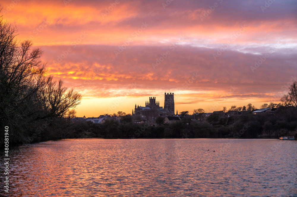 Cathedral of Ely with beautiful sunset colours in the sky infront of a lake
