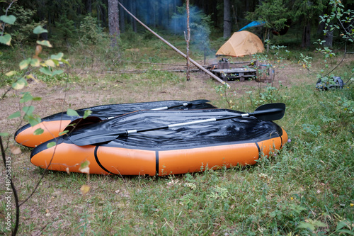 Two packrafts lie to dry in the camp, against the backdrop of a tent, in the forest, in summer. Active lifestyle concept. photo