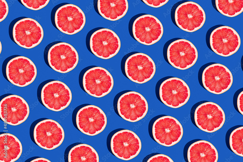 Minimal fruit pattern with grapefruit on blue  background. Creative  summer mood. Healty concept. Organic fruit. Flat lay. Trendy social mockup or wallpaper. - obrazy, fototapety, plakaty 