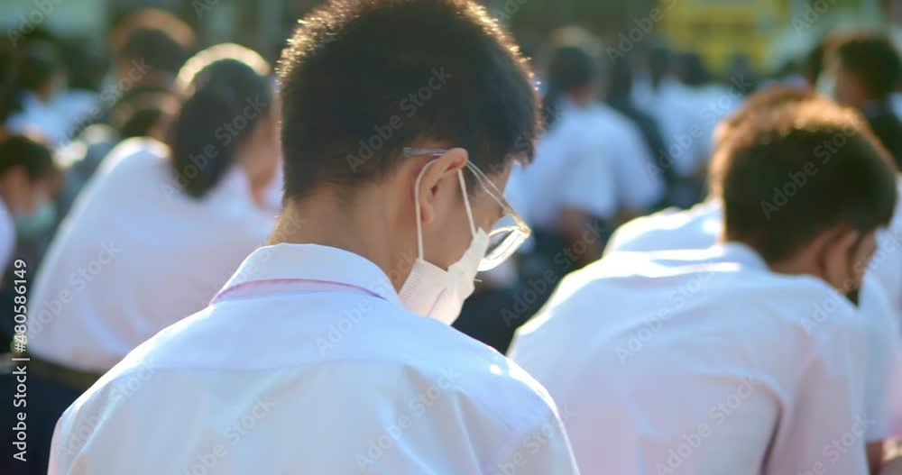Slow motion scene in the morning while the Asian high school students in white uniform wearing the masks sit in line during the Coronavirus 2019 (Covid-19) epidemic. Slow motion scene in the morning while the Asian high school students in white uniform wearing the masks sit in line during the Coronavirus 2019 (Covid-19) epidemic.