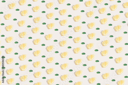 Sunlight summer pattern made with a yellow lemon slice and green leaves on a bright light background. Minimal summer concept.