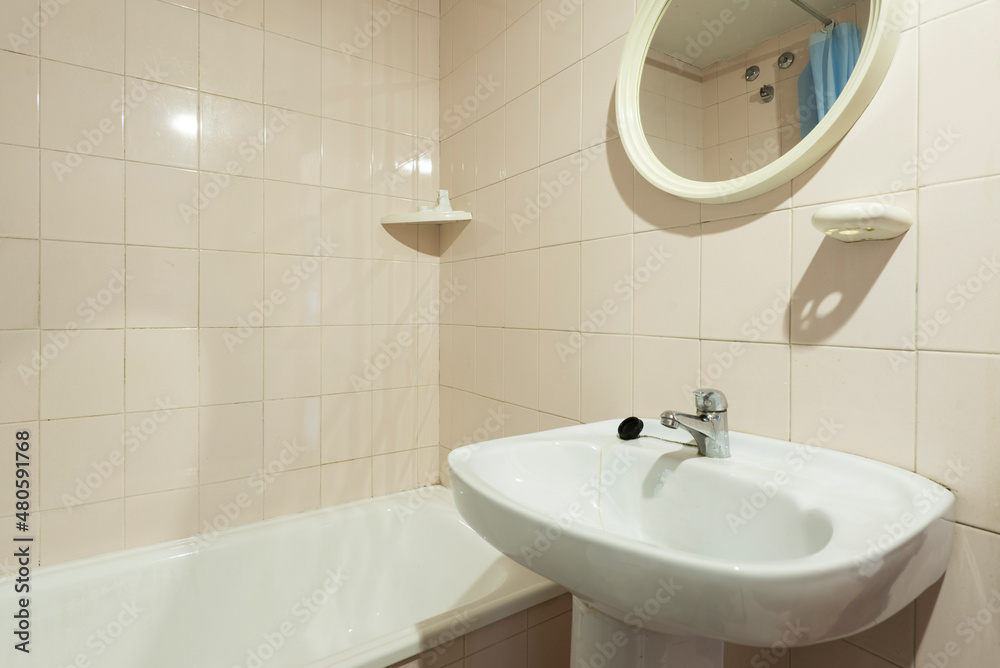 Spartan toilet with small circular mirror, earthenware sink and enamel bathtub Spartan toilet with small circular mirror, earthenware sink and enamel bathtub