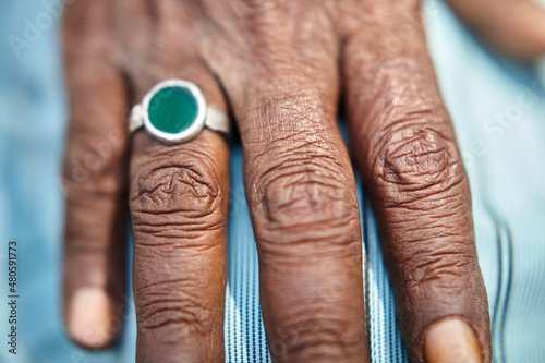 Old man hand in detail with green ring on finger. The color of the ring could be related to Islam. Outside. Close Up. 
