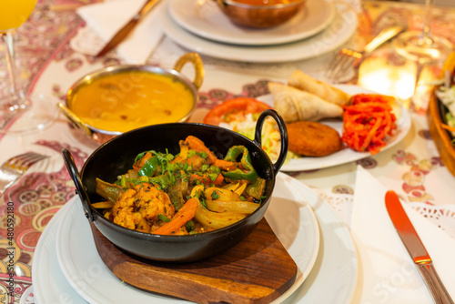 A medium spicy Indian dish consisting of chicken or lamb with fresh chillies, tomatoes, and onions. mixed roasted vegetables and mung sprout salads photo