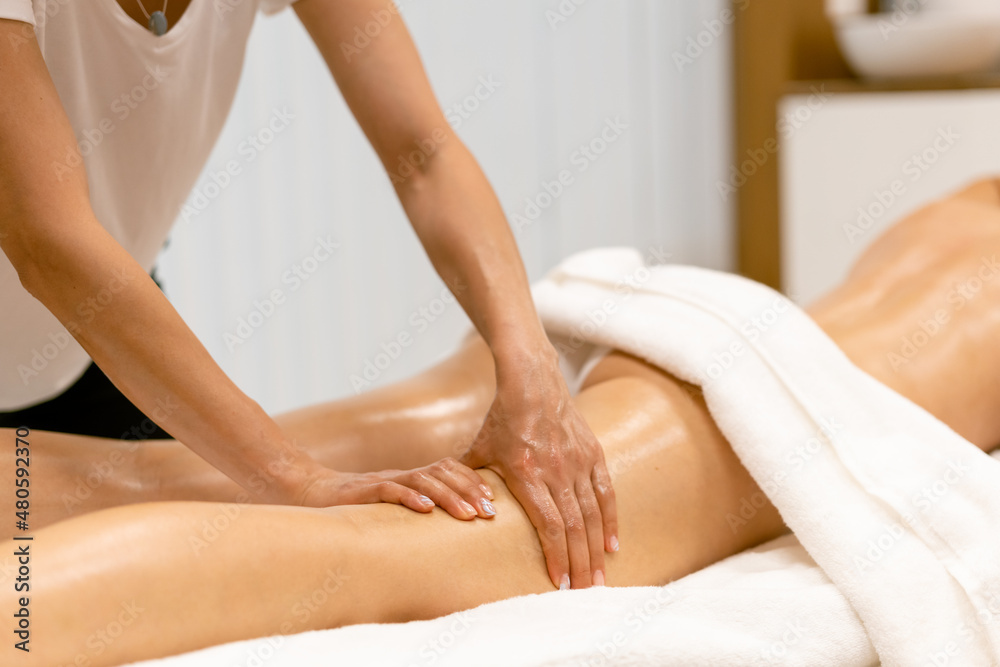 Obraz premium Beauty salon professional pouring oil from a massage candle on the back of his patient.