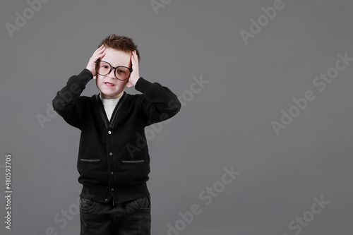 Sad unhappy schoolboy in eyewear having painful look, holding hand on his forehead. Frustrated sick child suffering form terrible headache