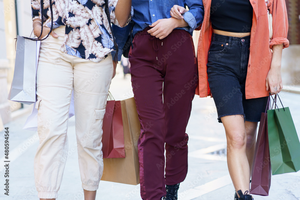 Crop anonymous trendy women walking on street with shopping bags Crop anonymous trendy women walking on street with shopping bags
