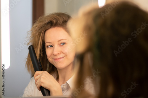 hair straightening,woman with iron with half curly and straight hair