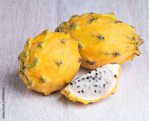 A piece of pitahaya and a whole pitahaya on a light wooden background