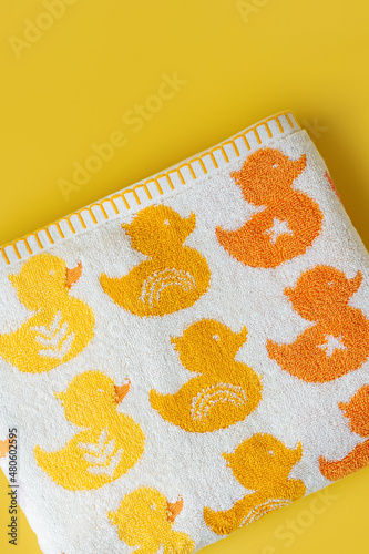 Baby towel with cute ducks on yellow background.
