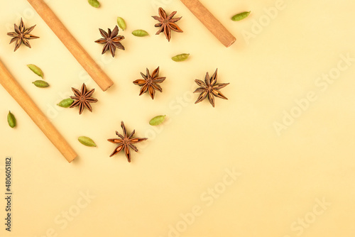 Cinnamon sticks, cardamom and star anise on a beige background, top view.