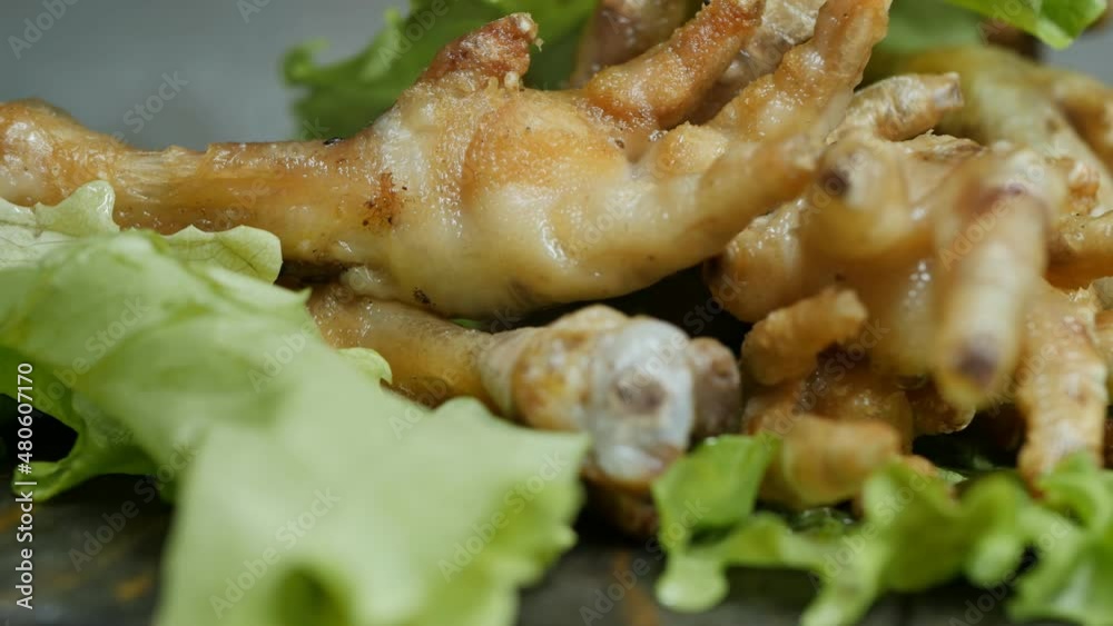 chicken legs cooked in hot oil in a golden crust and green lettuce rotate on a wooden table. Eating at a Korean restaurant. chicken legs cooked in hot oil in a golden crust and green lettuce rotate on a wooden table. Eating at a Korean restaurant.