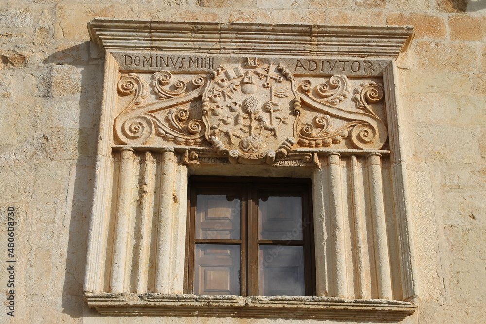 Fototapeta premium A window with a coat of arms and inscriptions carved in stone in a house in the town of Perazancas de Ojeda