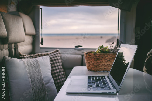 Tela Remote onilne work and smart working travel concept with laptop computer inside a van camper interior with beach view