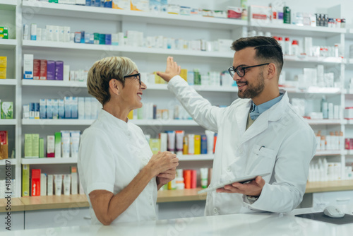 Happy young male pharmacist working with senior colleague