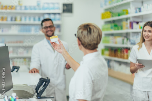 Male pharmacist working in a pharmacy with his female colleagues