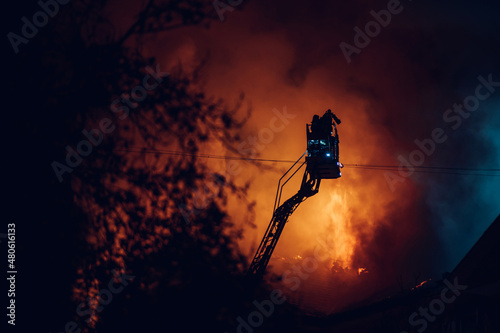 Firefighter on pull-out crane put out a fire in a burning building
