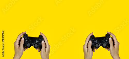 hands holding a black joystick, game controller isolated on yellow background
