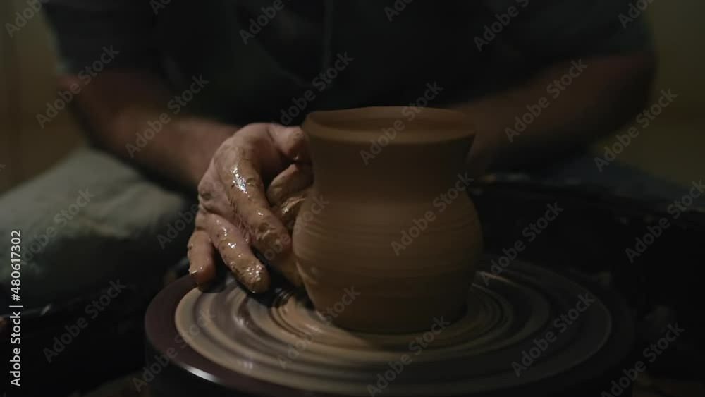 Artisan male hands shaping a jug from a clay on a potter's wheel in slow motion Artisan male hands shaping a jug from a clay on a potter's wheel in slow motion