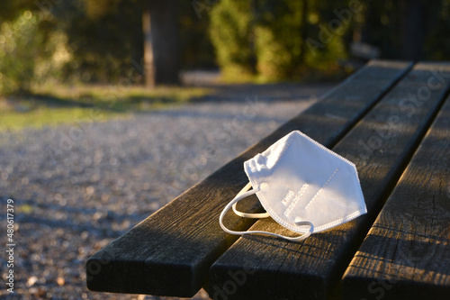 white used ffp2 protective mask abandoned on a park bench. Used protective masks abandoned during the Coronavirus pandemic on public places. photo