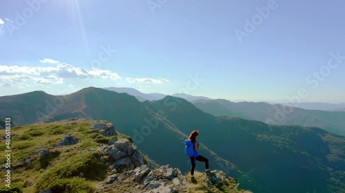 Aerial view of a woman on top of a mountain looking at the sunrise. Hiker girl celebrating scenic landscape enjoying nature vacation travel adventure. 4k