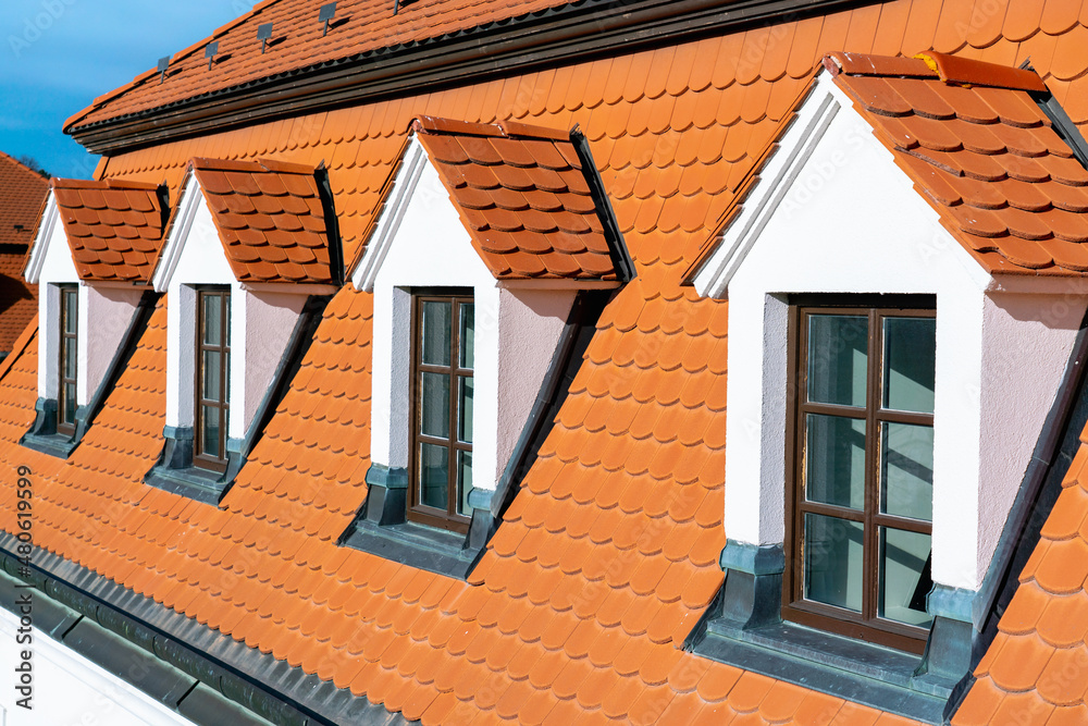 Dormer windows on tiled roof of old house on sunny day