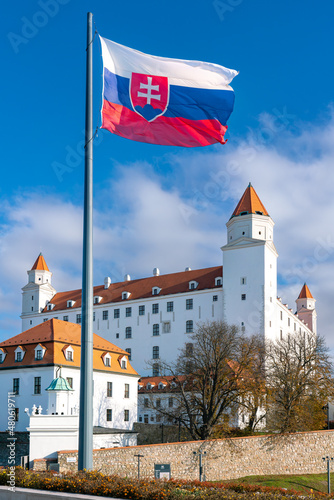 Bratislava castle with Slovak national flag flown on high flagpole, vertical shot from autumn