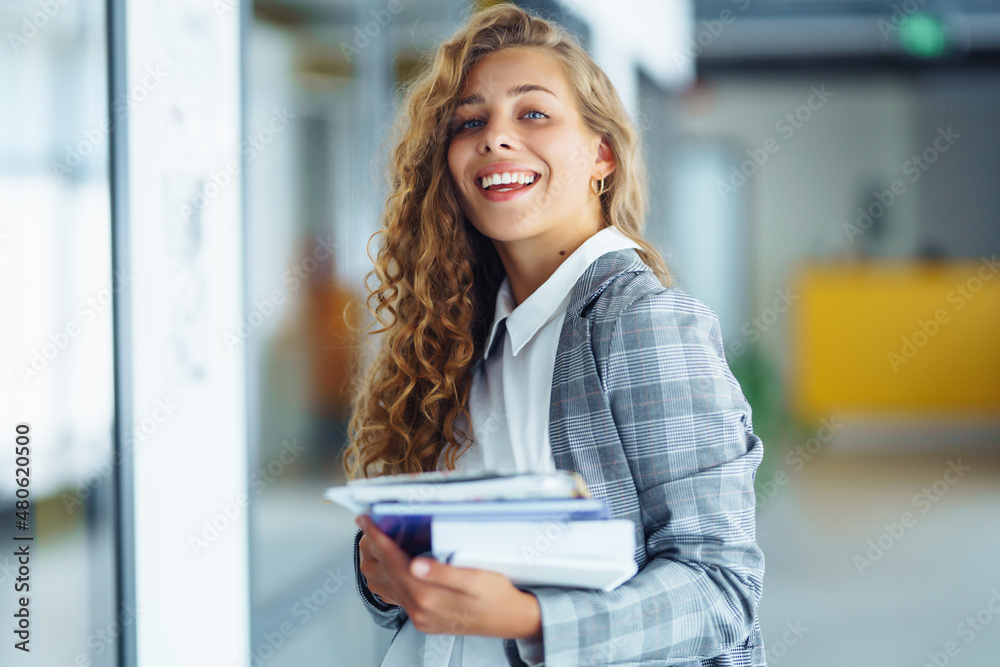 Fototapeta premium Portrait of business woman standing against office interior background. Female Entrepreneur. People, business, freelance, work concept