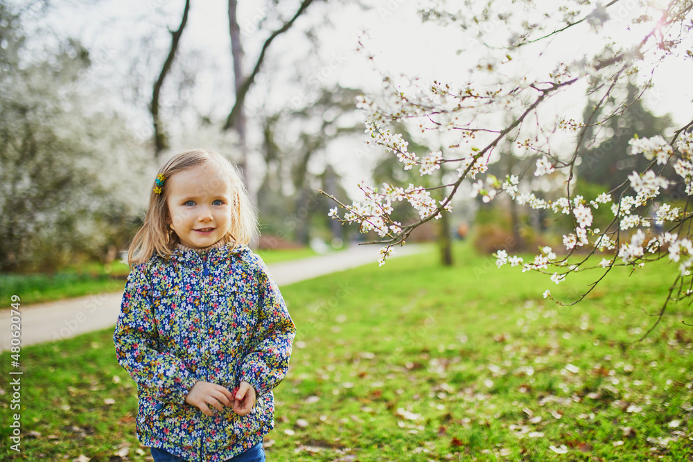 Adorable little girl enjoying nice and sunny spring day near apple tree in full bloom Adorable little girl enjoying nice and sunny spring day near apple tree in full bloom
