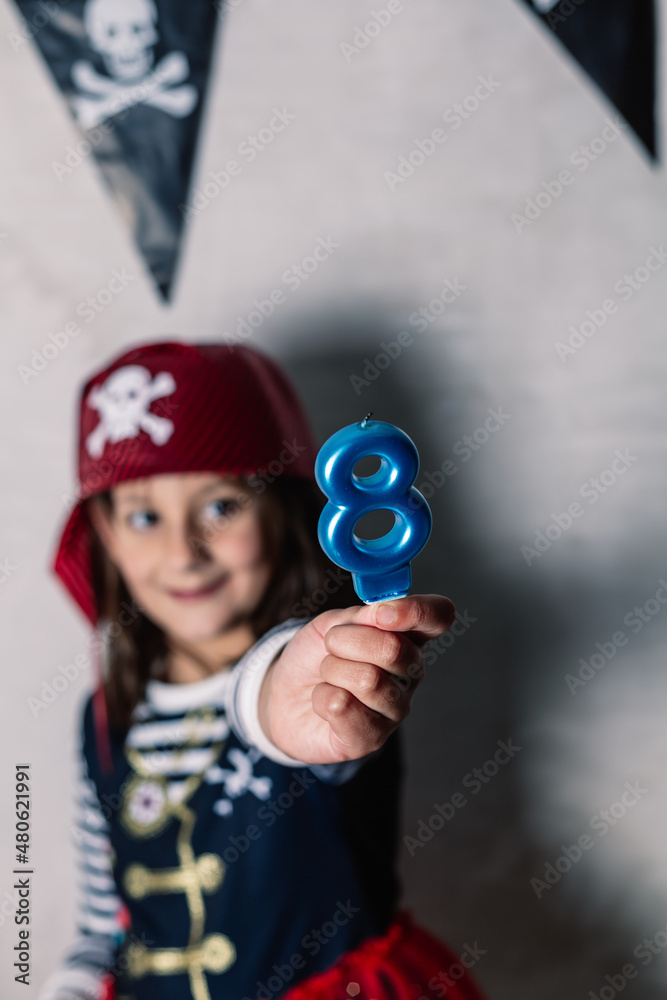 hand holding number eight candle, with unfocused girl in pirate costume hand holding number eight candle, with unfocused girl in pirate costume