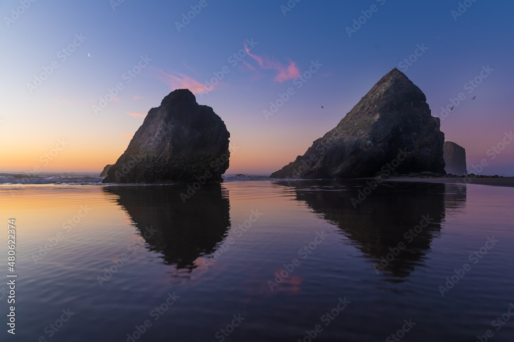 Beautiful seascape. Dust. There are two large stone rocks in the ocean. The sky is colored with orange rays of the setting sun. calm scenes. There are no people in the photo. Romance. Postcard.