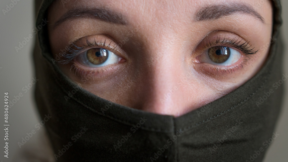 Female portrait of young girl wearing khaki balaclava, only eyes are visible, mandatory conscription, military, feminism, equality concept