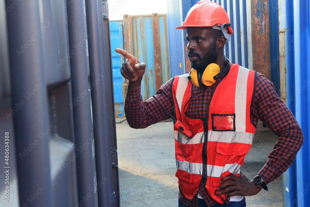 Close up of An African American handsome black engineer he is working in container box yard area of logistics transportation import export or shipping industry Close up of An African American handsome black engineer he is working in container box yard area of logistics transportation import export or shipping industry