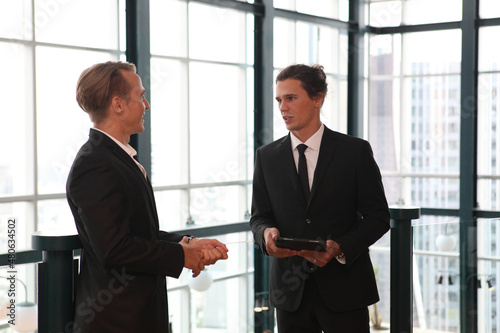 two young business people working and communicating while standing at the office with city building background. © sittinan