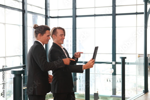 two young business people working and communicating while standing at the office with city building background. © sittinan
