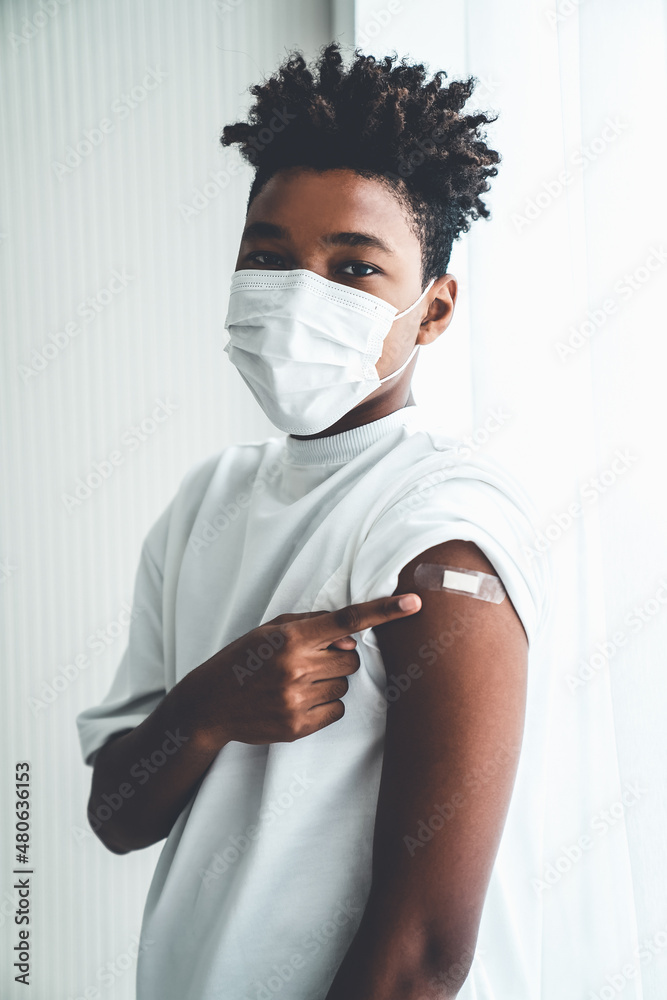 Leinwandbild Motiv - Blue Planet Studio : African American teenager showing COVID-19 vaccine bandage merrily in concept of coronavirus vaccination program to vaccinate citizen .