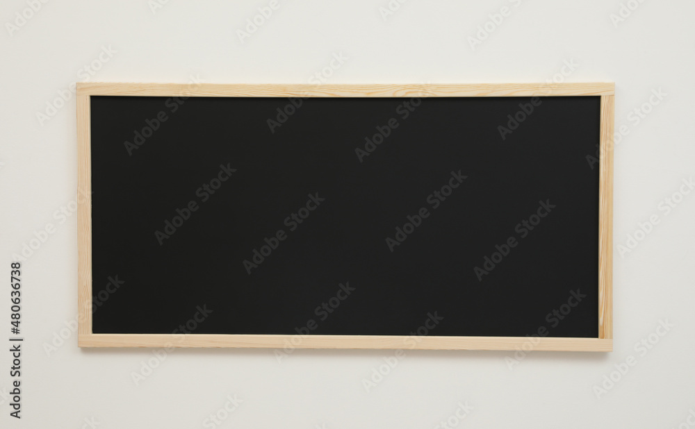 Clean black chalkboard hanging on white wall Clean black chalkboard hanging on white wall