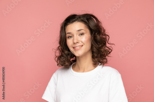 Portrait of a happy young woman on pink background, curly hair, caucasian girl