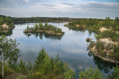 An old granite quarry and a formed lake with a sandy-rocky shore and tree-covered islands.