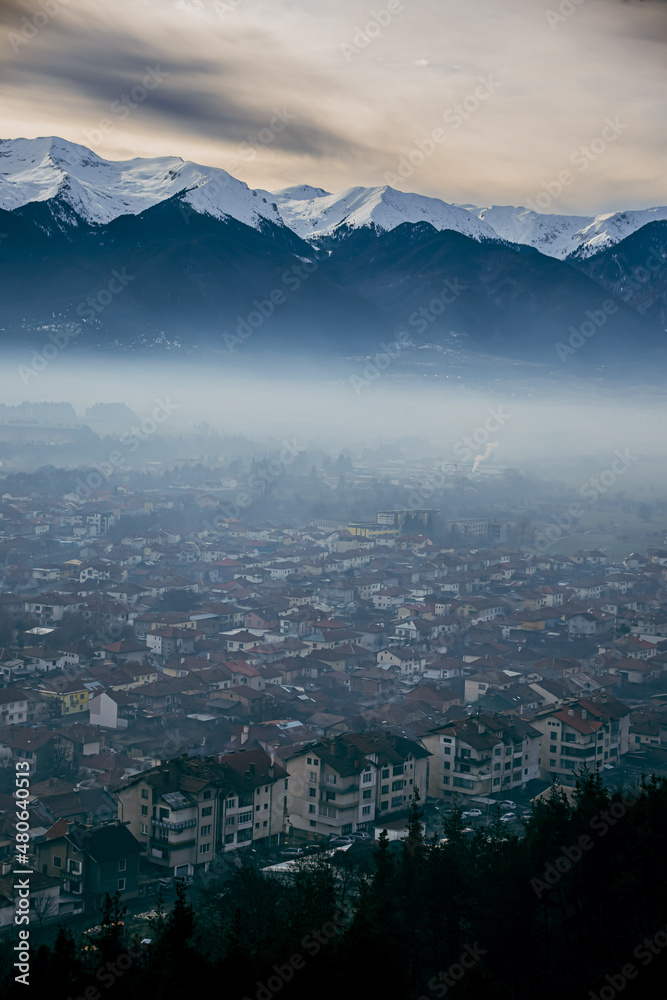 Pirin mountain, Bulgaria. Covered in snow peak in winter skiing season. Mist fog and Razgrad city below the mountain