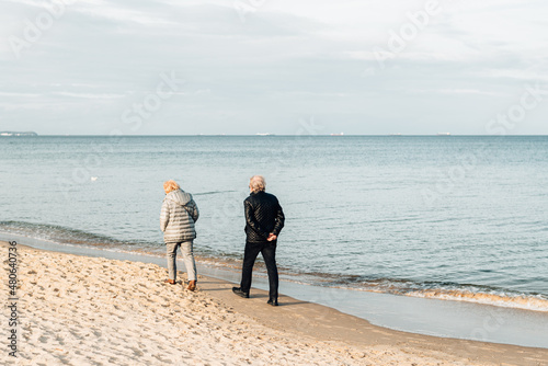 Elderly couple walks along the shore of the cold sea. Love in old age. Travel to Scandinavia.