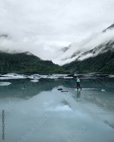 Adventure Girl Exploring Glacier Lake with Icebergs in Valdez Alaska. Blue and turquoise water below mountains in gorgeous valley