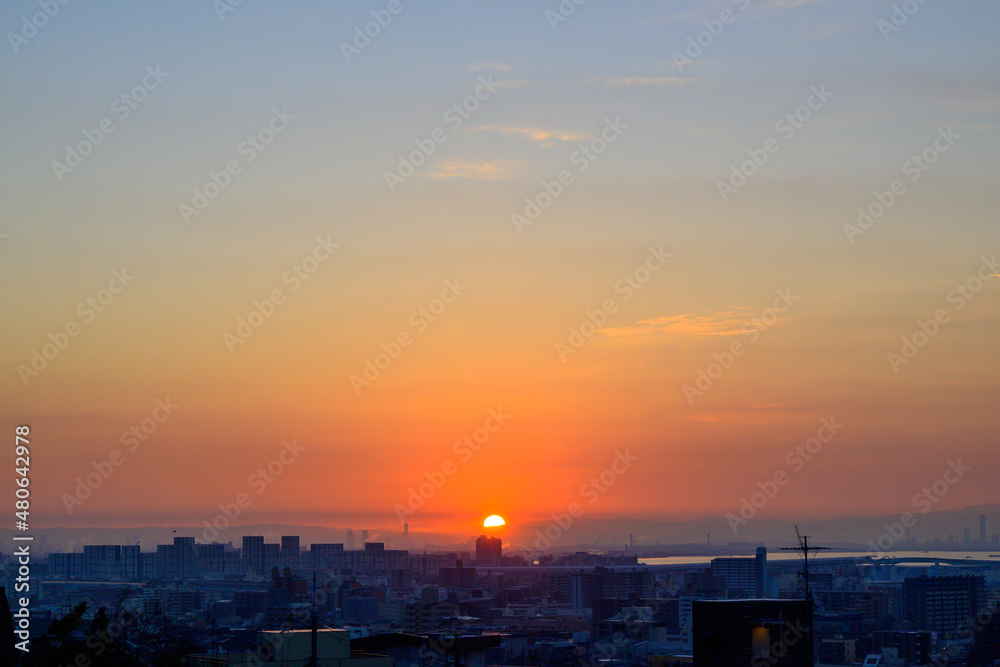 都市の夜明け。太陽が昇りあたりはオレンジ色に染まる。神戸市東灘区の高台岡本梅林公園から神戸市街地、大阪方面を臨む。