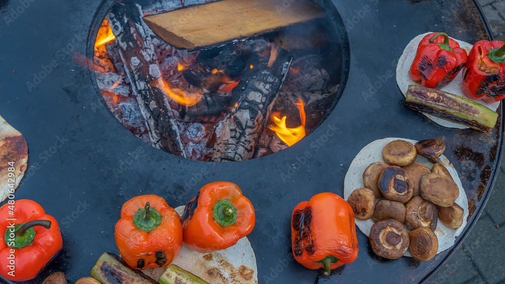 Cooking grilled vegetables on a street stove during the fair. Sale of vegetarian grilled food at the festival. Cooking grilled vegetables on a street stove during the fair. Sale of vegetarian grilled food at the festival.