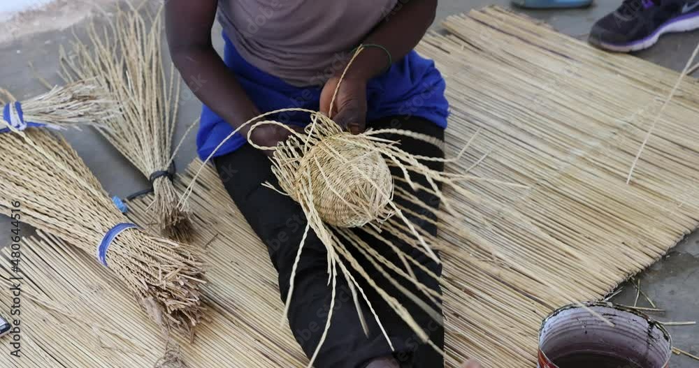 African Woman weaving a grass basket traditional village Ghana. Northern Ghana art and craft village specializing in pottery, baskets, leather and painting. Income from tourism and export.