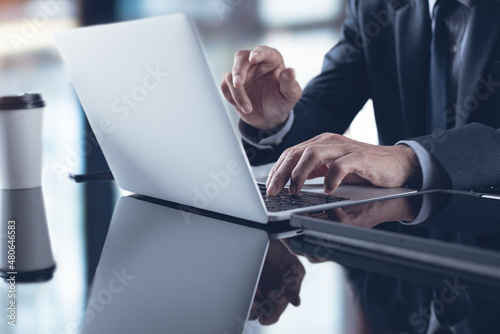 Businessman in black suit working on laptop computer at modern office and have a discussion during online meeting