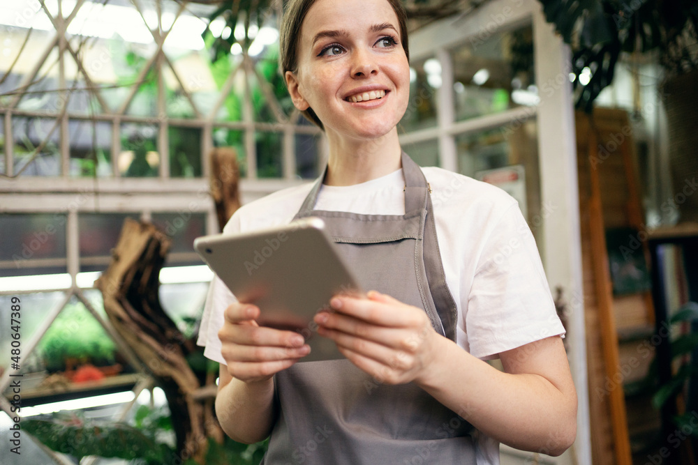 The florist sells flowers and plants for the home in the studio. The gardener woman uses the Internet site information.